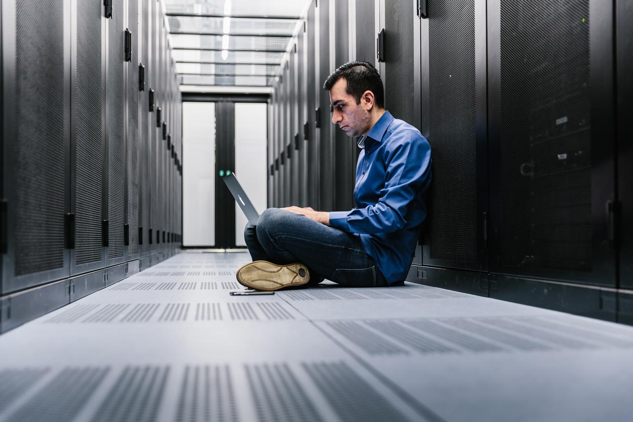 Image of a colleague sitting on the floor in front of our server rack.